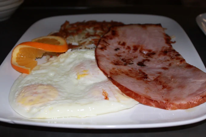 Grilled ham steak with eggs, hash browns and orange slices